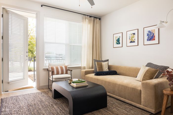 Apartment living room with sofa and patio access at The Prado apartments in Del Valle, TX