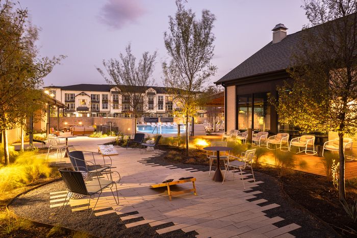 Landscaped courtyard with lounge seating at dusk at The Prado apartments in Del Valle, TX