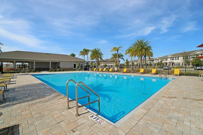outdoor pool with yellow chaise loungers