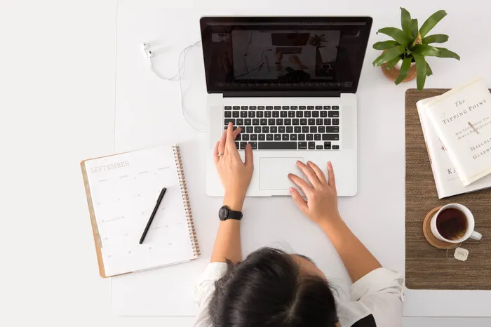 woman and laptop with tea next to it