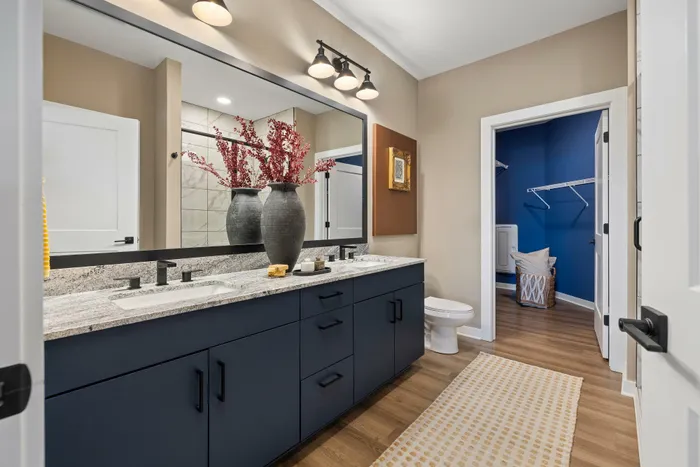 Model residence, bathroom with wood plank flooring, double vanity, blue cabinets, large closet
