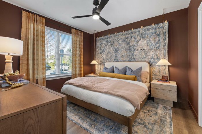 Model residence, large bedroom with wood plank flooring, ceiling fan, large windows