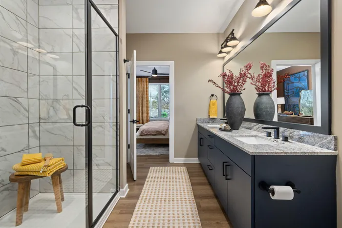 Model residence, bathroom with double vanity, semi-frameless shower, wood plank flooring, built-in linen storage