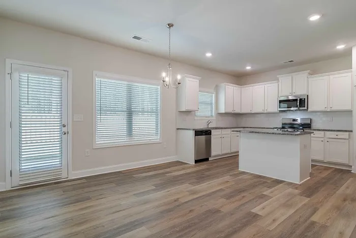 vacant dining room and kitchen with white cabinets