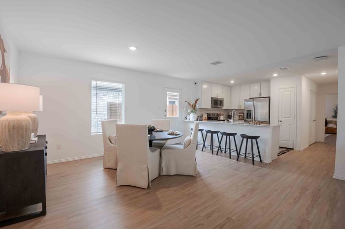 dining room with white chairs looking into kitchen