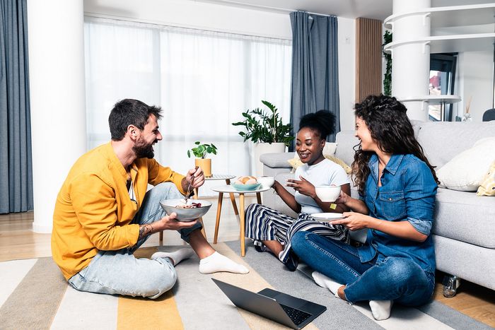 three people sitting on the floor eating