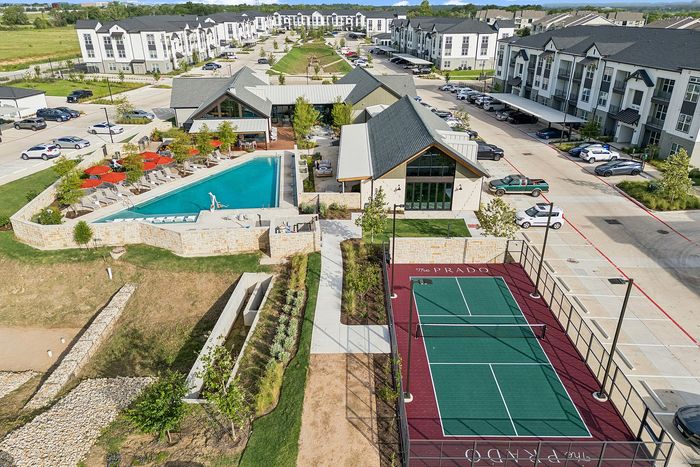 Aerial view of pool, clubhouse and pickleball court at The Prado apartments in Del Valle, TX