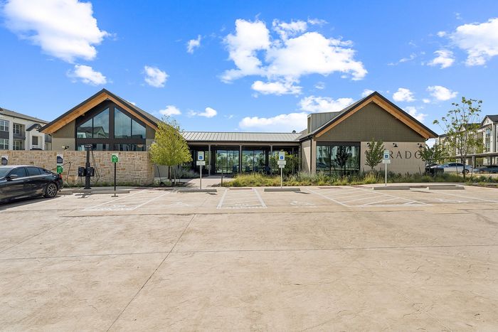 Leasing office exterior with gabled roofline at The Prado apartments in Del Valle, TX
