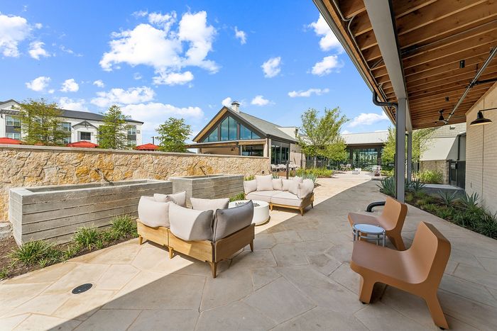Covered poolside lounge with seating at The Prado apartments in Del Valle, TX
