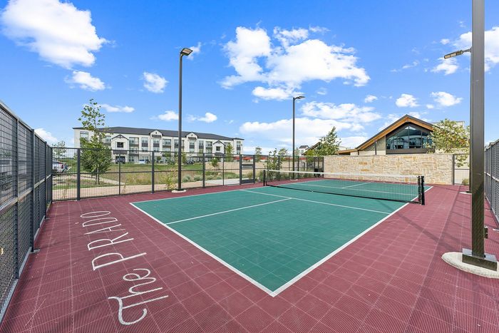 Fenced pickleball court with lighting at The Prado apartments in Del Valle, TX
