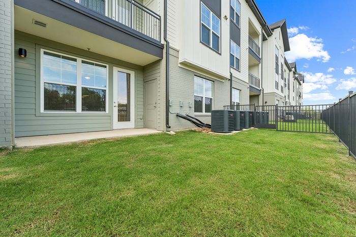 Private fenced yard with green grass at The Prado apartments in Del Valle, TX