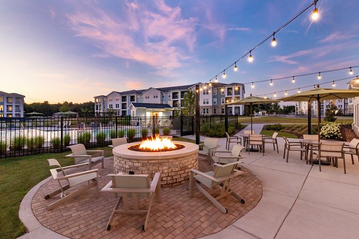Outdoor fire pit lounge with comfortable seating and ambient lighting at sunset.