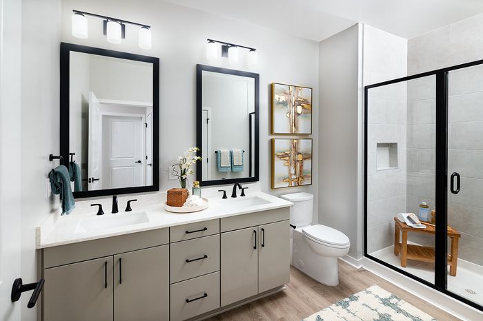 Modern apartment bathroom with double vanity sinks, large mirrors, and contemporary finishes.