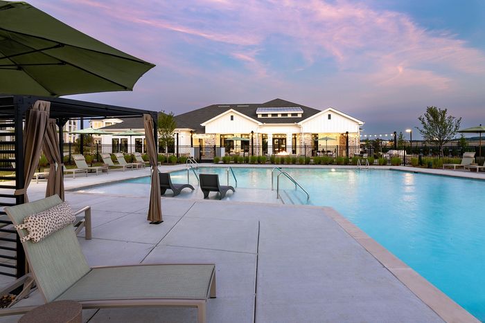 Resort-style apartment swimming pool with spacious tanning deck, poolside lounge chairs, and sunset views.