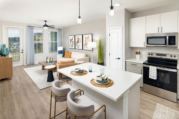 Bright open-concept apartment with modern kitchen, spacious living area, breakfast bar, and large windows.