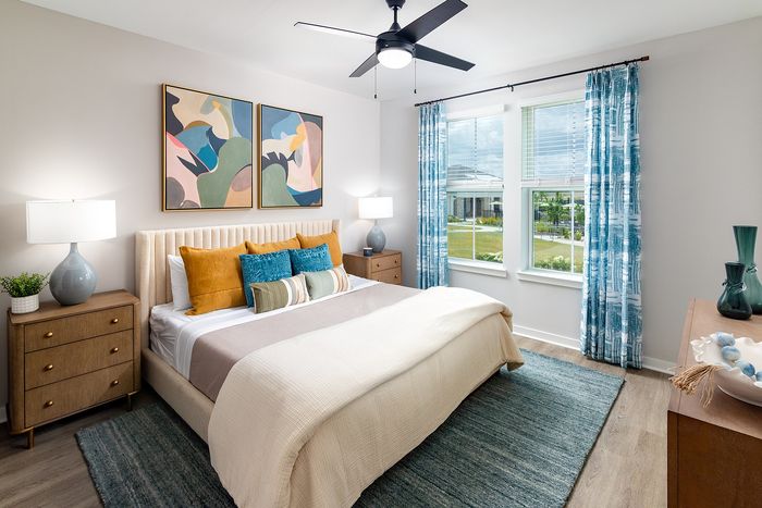 Bright apartment bedroom with expansive windows, modern furnishings, and comfortable bedding.