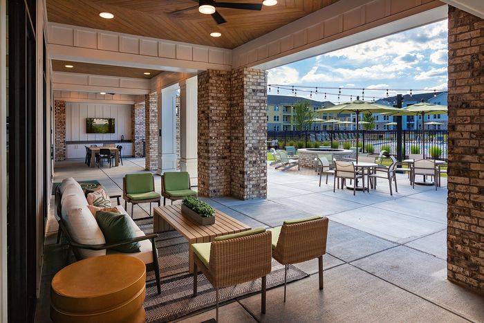Covered outdoor resident lounge with comfortable seating and views of the surrounding outdoor amenities.