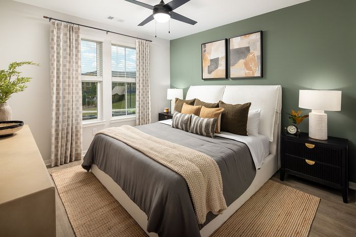 Contemporary apartment bedroom with large windows, neutral furnishings, and soft natural lighting.