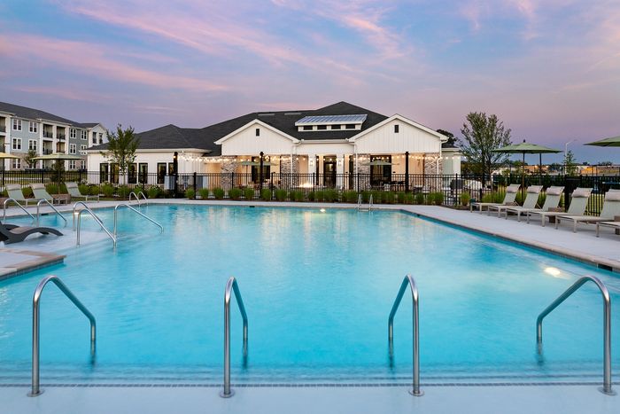 Resort-style apartment swimming pool with spacious tanning deck, poolside lounge chairs, and sunset views.