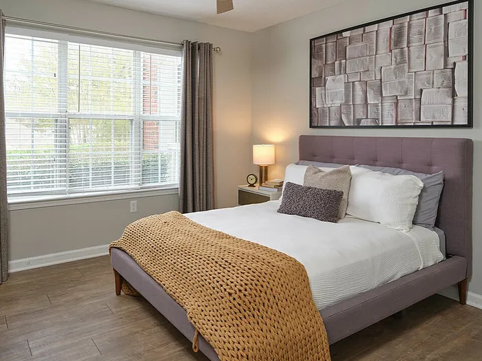 Bright and cozy bedroom with modern decor, featuring a plush bed, large window with natural light, and stylish artwork.