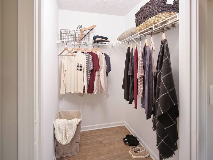 Spacious walk-in closet with wooden flooring, featuring neatly organized clothes and chic storage baskets, offering a blend of functionality and style.