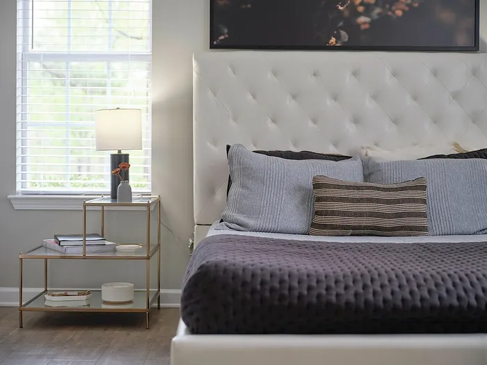 Inviting bedroom with a plush, tufted headboard, modern side table, and elegant lamp, creating a cozy and luxurious atmosphere.