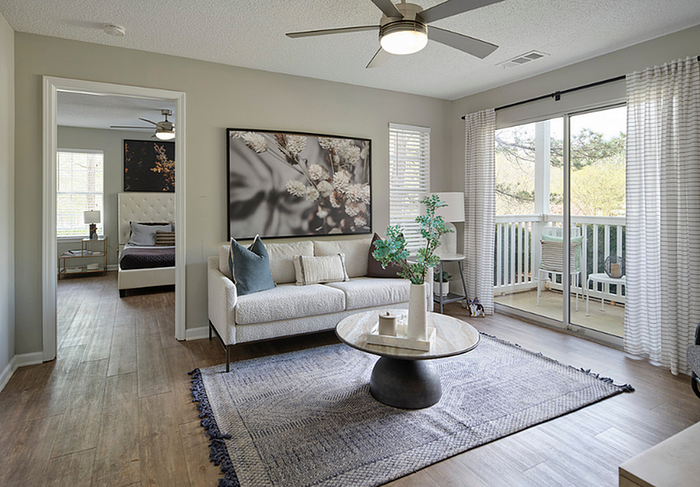 Bright and cozy living room with modern decor, plush sofa, and sleek coffee table. Large glass doors open to a sunny balcony, enhancing the airy ambiance.