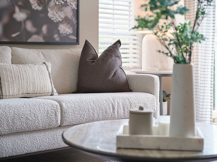 Inviting living room with a cozy beige sofa, elegant cushions, and a chic marble coffee table adorned with a stylish vase.