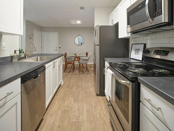 Sleek modern kitchen with stainless steel appliances, chic countertops, and open layout leading to dining area.
