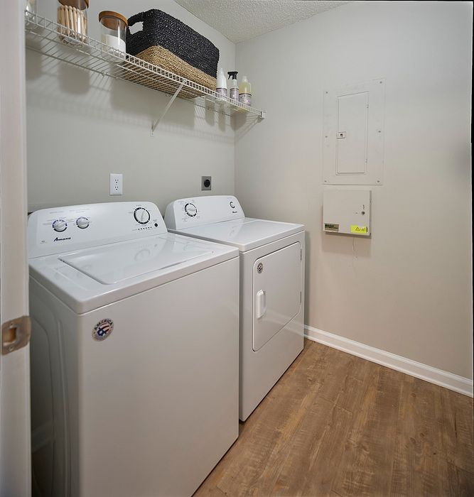 Modern laundry room with sleek washer and dryer, natural wood flooring, and organized shelving for a clean, efficient space.