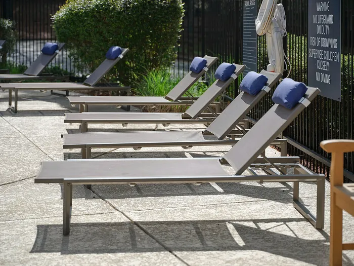Inviting outdoor lounge area with stylish sun loungers and luxurious blue cushions, perfect for relaxation in a sunny, tranquil setting.