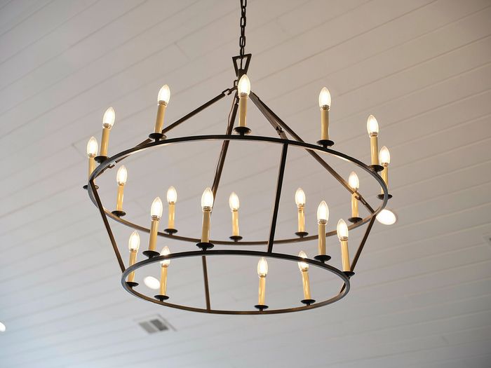 Elegant black metal chandelier with glowing candle-style lights, adding a touch of sophistication to the room's ambiance.