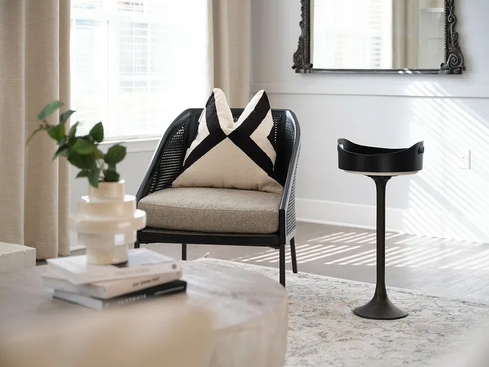Chic living room with a cozy armchair, stylish accent table, and elegant decor elements, bathed in natural light.