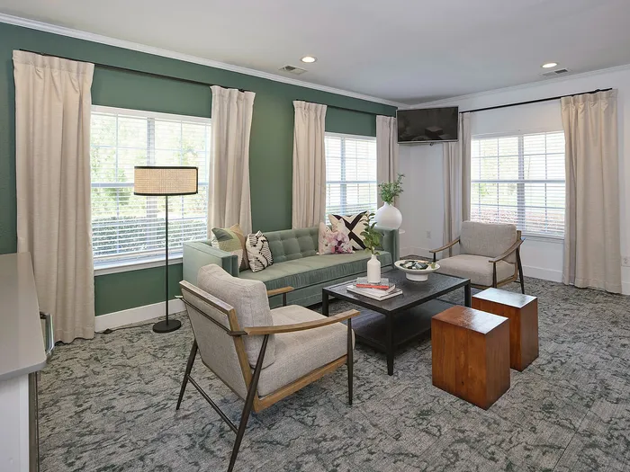 Inviting living room with modern furniture, stylish green accent walls, and abundant natural light from large windows.