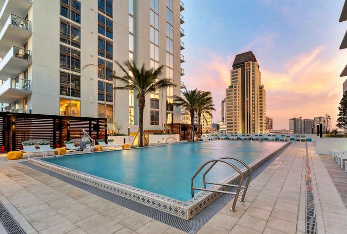 Luxurious rooftop pool with palm trees and city skyline views, perfect for relaxation and leisure.
