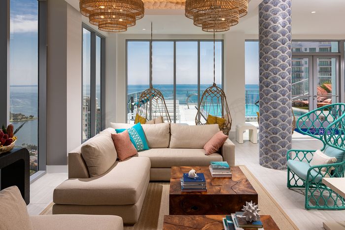 Luxurious open-concept living room with panoramic ocean views, modern furnishings, and chic hanging chairs, exuding elegance and relaxation.