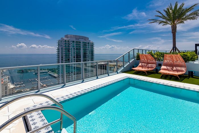 Luxurious rooftop pool with stunning ocean views and elegant lounge chairs, perfect for relaxation in a sophisticated setting.