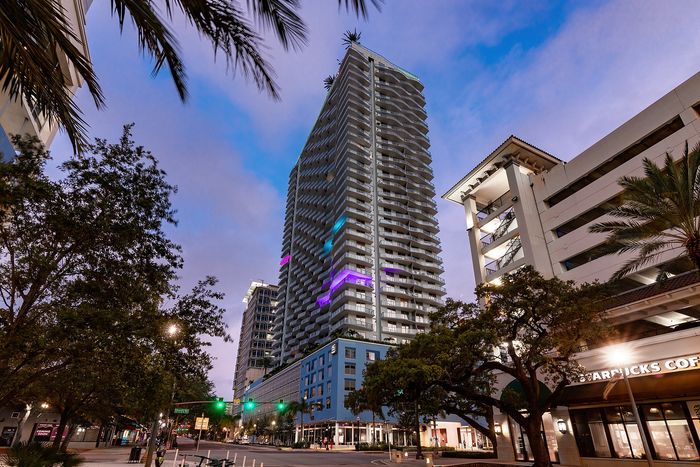 Stunning urban high-rise with modern architecture, featuring vibrant LED lighting against a twilight sky.