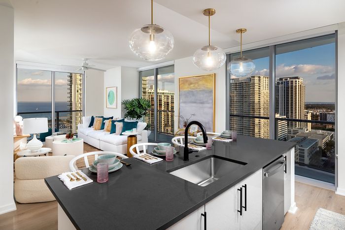 Luxurious modern apartment with open-concept kitchen, cozy living room, and stunning city views through floor-to-ceiling windows.