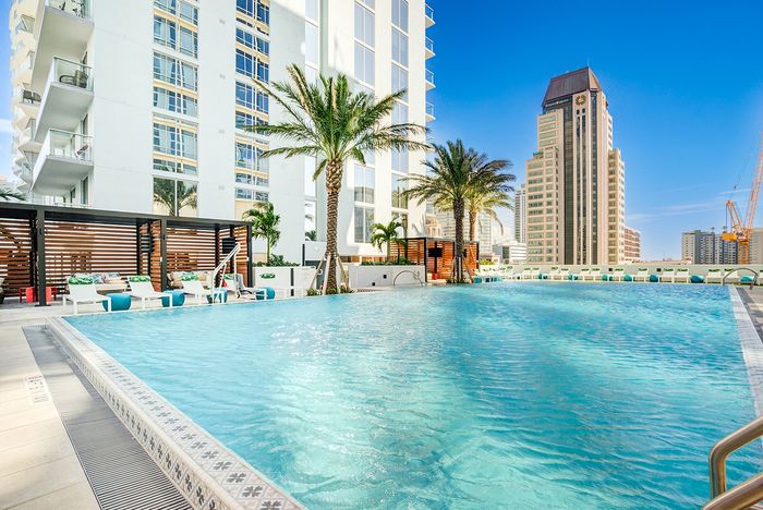 Luxurious rooftop pool with palm trees and modern cityscape views, perfect for a relaxing urban retreat.