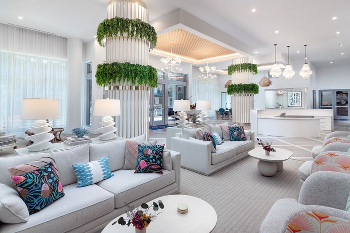 Luxurious and modern apartment living room with stylish sofas, vibrant decorative pillows, elegant lighting, and lush greenery, offering a sophisticated and welcoming ambiance.