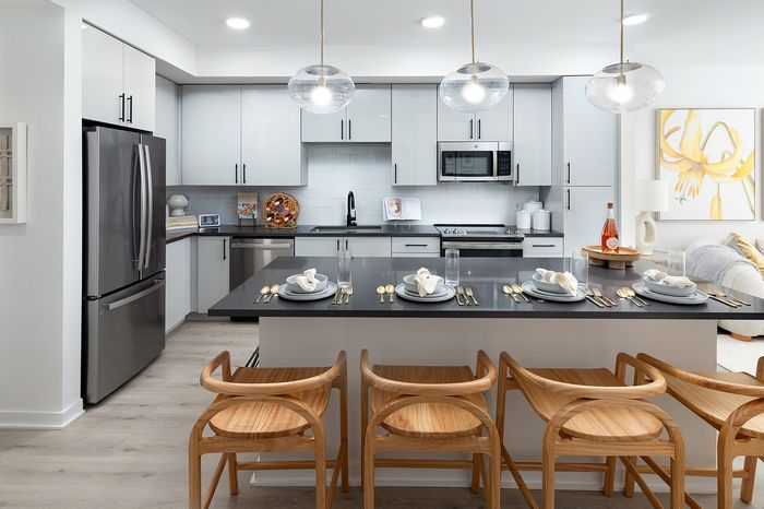 Modern kitchen showcasing sleek cabinetry, stainless steel appliances, and a stylish island with elegant dining setup.