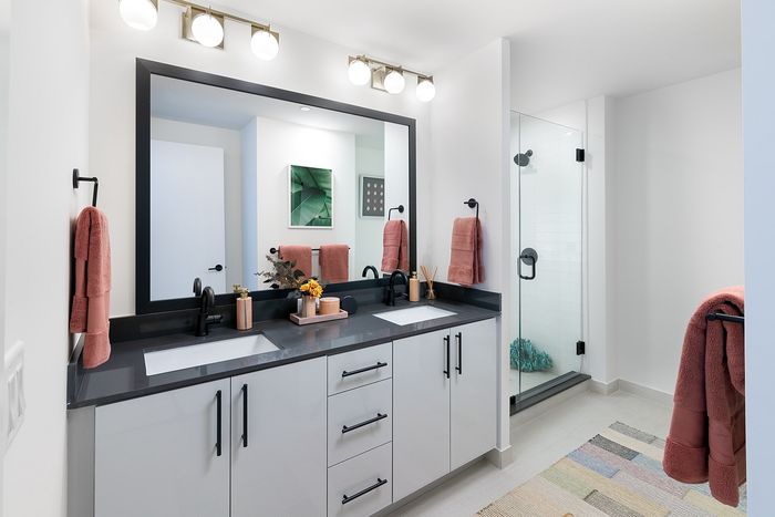 Sleek modern bathroom featuring dual sinks, elegant mirror lighting, and a spacious glass-enclosed shower with stylish decor.