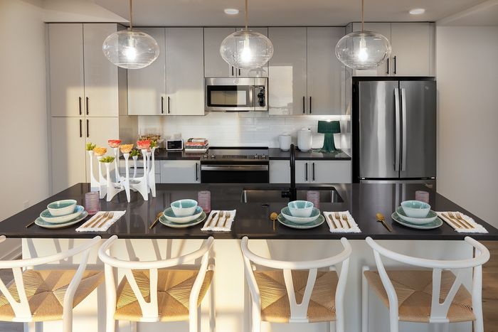 Modern kitchen with elegant pendant lighting, sleek stainless steel appliances, and a chic breakfast bar set for four.