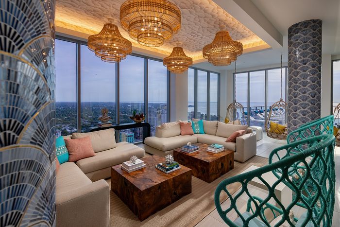Luxurious living room with elegant chandeliers, panoramic city and ocean views, and cozy seating, perfect for entertaining in style.