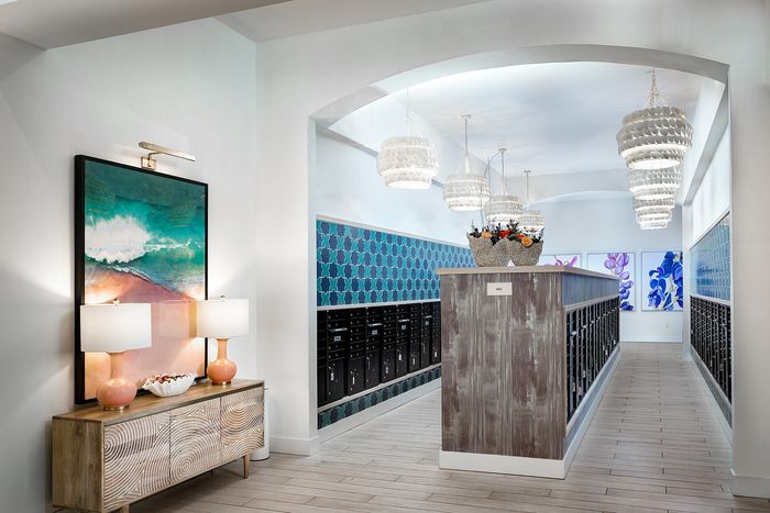 Elegant apartment lobby featuring modern decor, ambient lighting, and stylish artwork, with a wall of mailboxes.