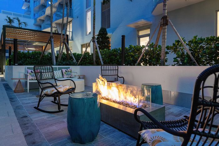 Chic outdoor patio with cozy modern seating and a stylish fire pit, perfect for evening relaxation.