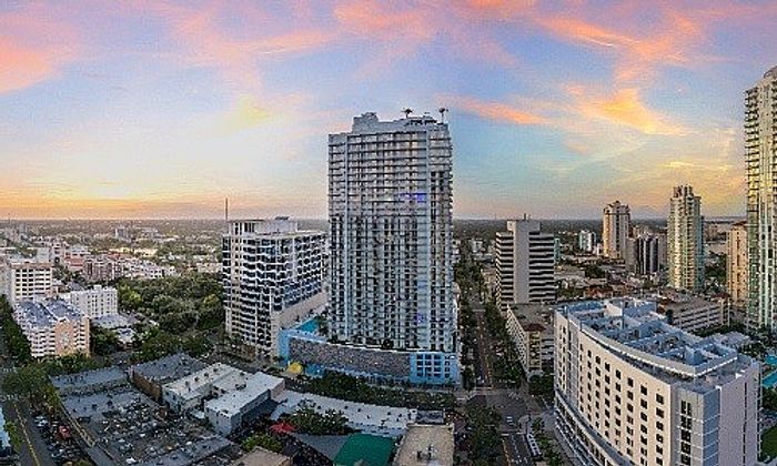 Stunning aerial view of a vibrant cityscape with modern high-rise buildings and a breathtaking sunset sky.