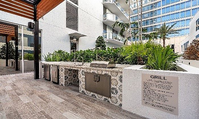 Modern outdoor grilling area with sleek countertops and lush greenery in a luxury apartment complex.