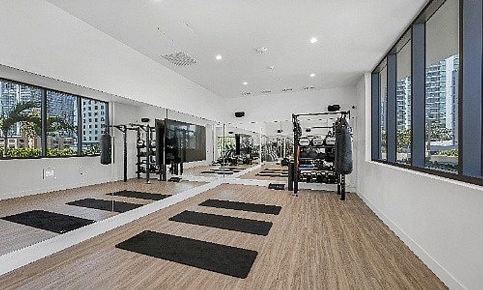 Modern fitness room with large mirrors, exercise mats, and gym equipment, offering a bright and inviting workout space.